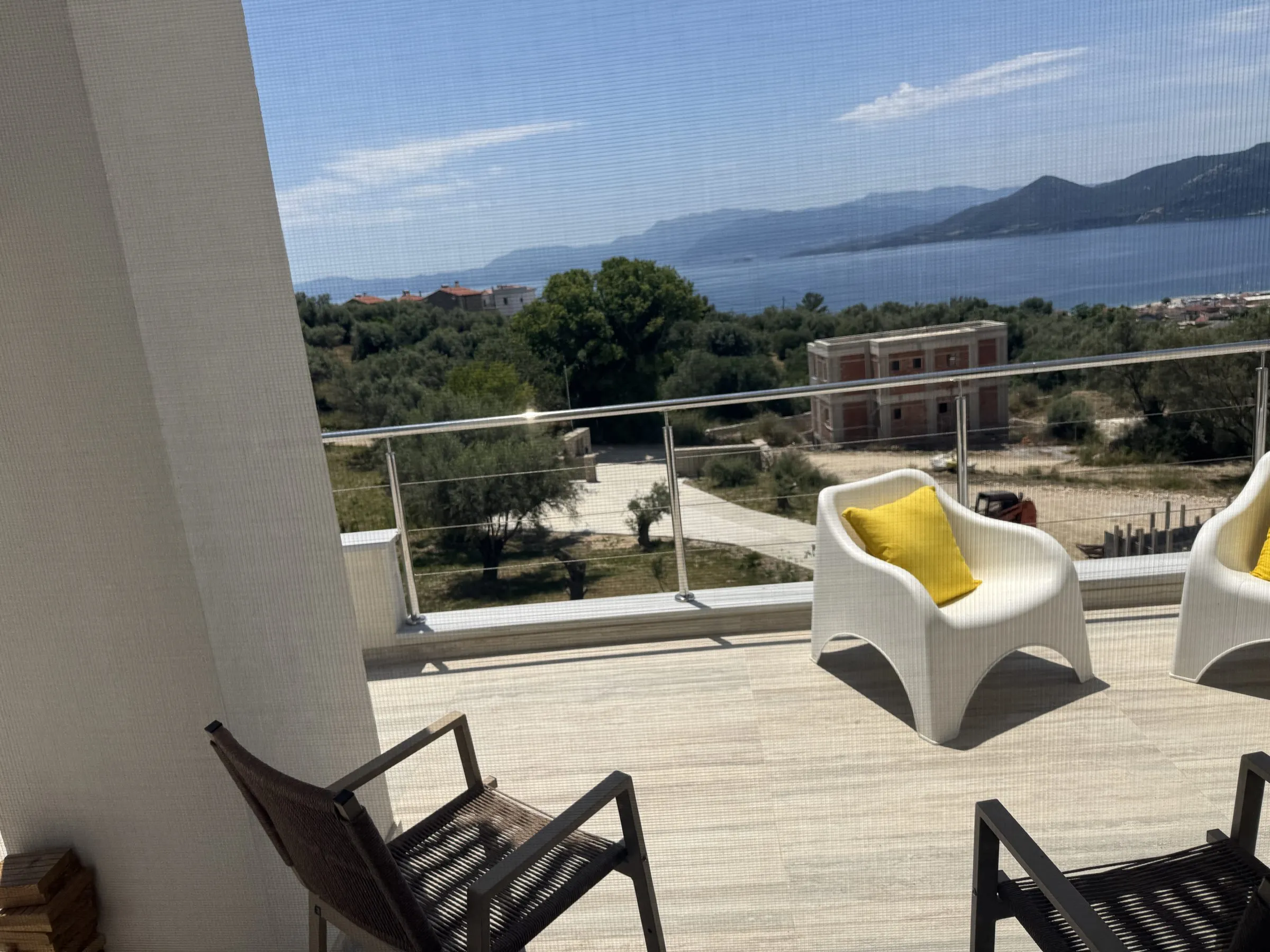 Upper balcony at Villa Prima with cushioned seating overlooking olive groves and the Ionian Sea.
