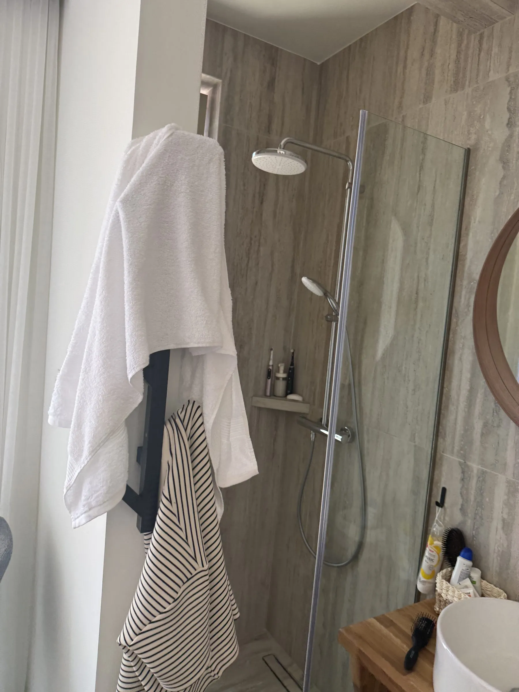 En-suite bathroom at Villa Prima with a walk-in rain shower, stone-look walls and a wood vanity.