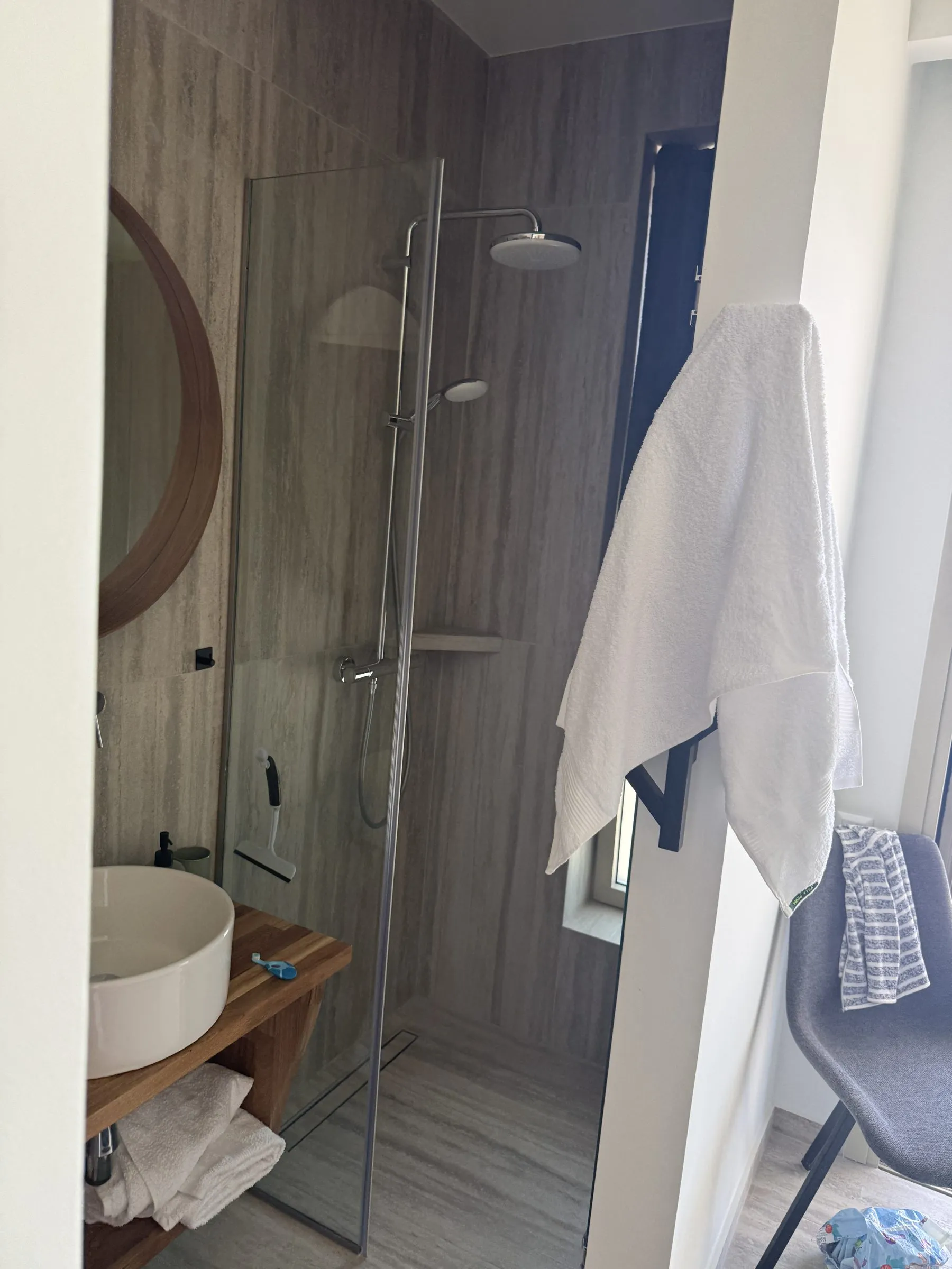 Walk-in shower and wood vanity in a stone-tiled bathroom at Villa Prima.